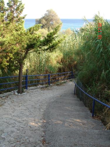 a path with a blue fence next to the ocean at De La Plage Hotel Koroni in Koroni