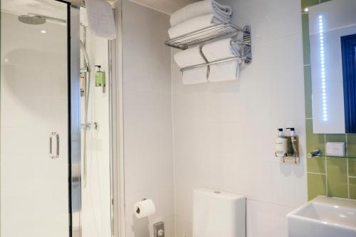 a bathroom with a shower and a toilet and towels at The Wellington Hotel in London