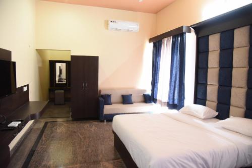 Un dormitorio con una cama, un televisor y un sofá. en Chitrakoot Garden and Resorts, en Pushkar