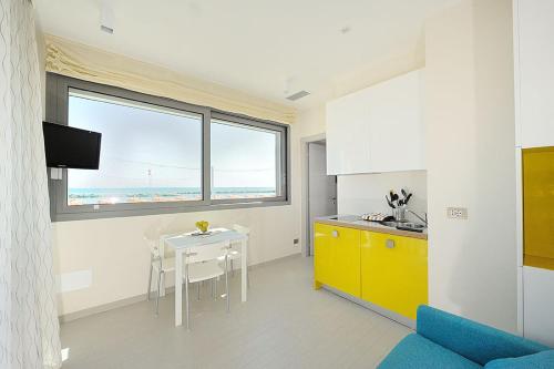 a kitchen with a table and a yellow cabinet at Hotel & Residence Cavalluccio Marino in Rimini