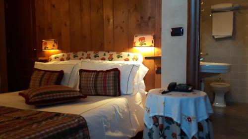 a bedroom with a bed with a table and a sink at Villa Novecento Romantic Hotel - Estella Hotel Collection & Experience in Courmayeur