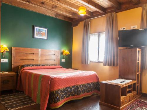 a bedroom with a bed and a flat screen tv at Apartamentos Rurales Les Martes in Felechosa