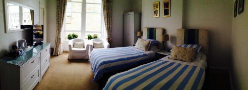 
a bedroom with two beds and two windows at Doune Guest House in St. Andrews
