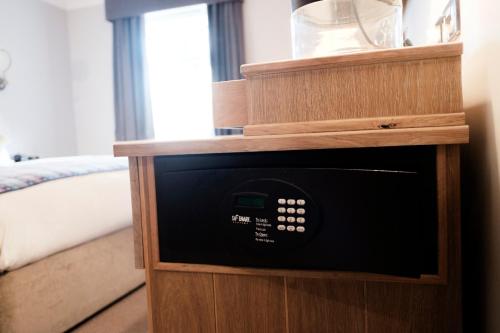 a microwave in a wooden cabinet in a bedroom at The White Hart Hotel in Kingston upon Thames