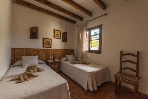 a bedroom with two beds and a chair and a window at La Brujita in Frontera