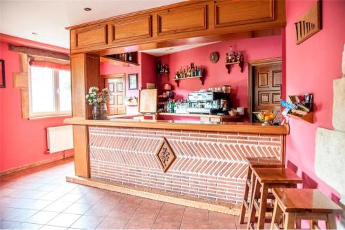 a restaurant with pink walls and a counter with chairs at Posada Rural La Sosiega in Argüeso