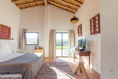 a bedroom with a bed and a desk and a window at Herdade da Maxuqueira in Gavião