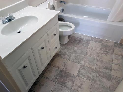 a bathroom with a sink and a toilet and a tub at Westgate Inn in Portage La Prairie