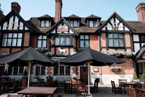 a building with tables and umbrellas in front of it at The White Hart Hotel in Kingston upon Thames