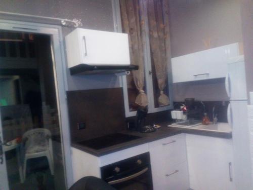 a kitchen with white cabinets and a black stove at Loft Les Tourelles in Andon