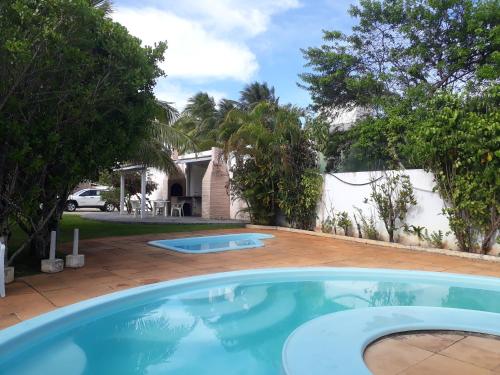 a large swimming pool in a yard with trees at Village a Beira Mar na Praia da Espera in Itacimirim