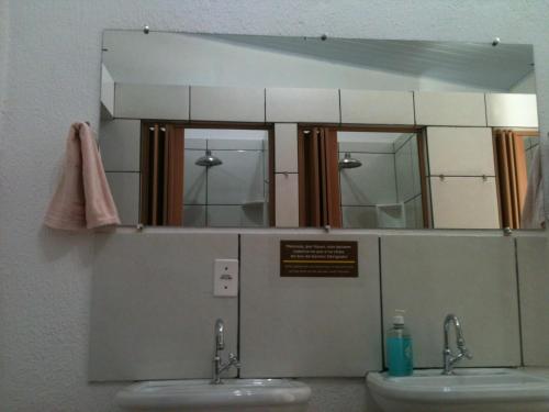 um espelho por cima de dois lavatórios numa casa de banho em Casamatta Hostel em Pirenópolis