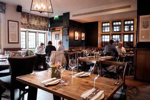 un restaurant avec des tables en bois et des personnes assises à table dans l'établissement The White Hart Hotel, à Kingston upon Thames
