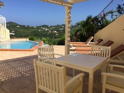 a patio with a table and chairs and a swimming pool at South Sea House in Cap Estate