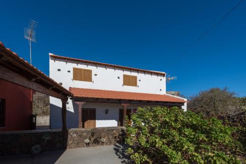 een wit huis met een rood dak en een tuin bij Casa La Fuente in Isora