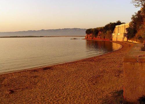a beach next to a body of water at Apartments Lolo in Privlaka
