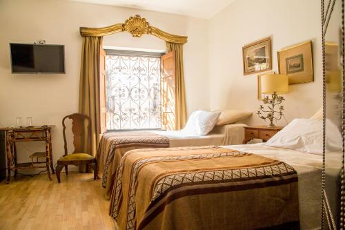 a hotel room with two beds and a window at Virreinato Hotel Boutique in Cordoba
