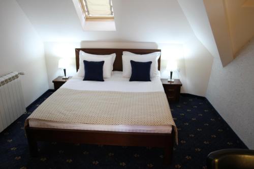 a bedroom with a large bed with blue pillows at Hotel Trebjesa in Nikšić