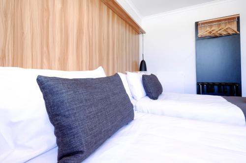 a bedroom with two white beds and a blue wall at No. 9 Hotel in Auckland