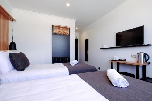 a hotel room with two beds and a flat screen tv at No. 9 Hotel in Auckland