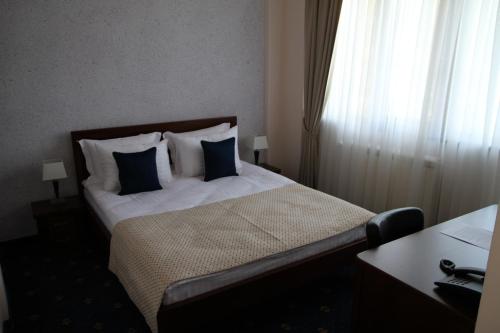 a hotel room with a bed with blue and white pillows at Hotel Trebjesa in Nikšić