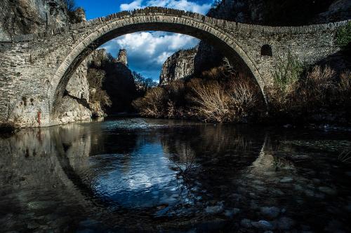 a stone bridge over a body of water at En Chora Vezitsa in Vitsa