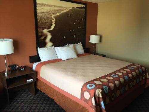 a hotel room with a large bed with a picture on the wall at Super 8 by Wyndham College Station in College Station