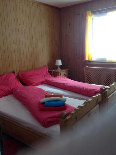 ダボスにあるBergheim Mattaのピンクのシーツとタオルが備わる客室内のベッド2台