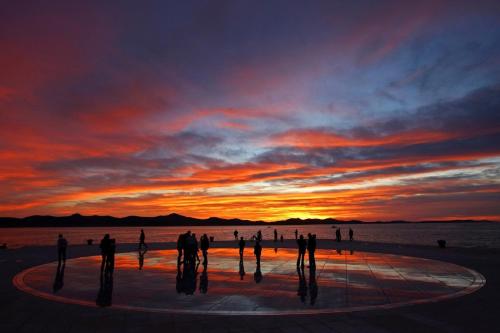 a group of people standing in front of a sunset at Studio Apartments Pavin in Zadar