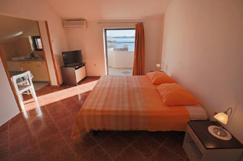 a bedroom with a bed with orange sheets and a window at Studio Apartments Pavin in Zadar