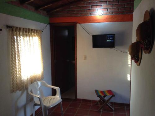 Habitación con puerta, silla y TV. en Villa Liliana Lodge Mesa de los Santos, en Los Santos
