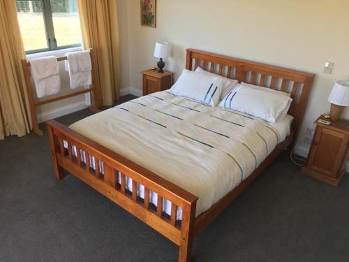 a bedroom with a large wooden bed with white sheets at Pahau Downs in Culverden