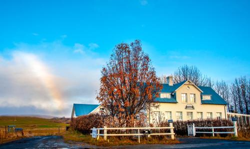 a rainbow in front of a house with a tree at Guesthouse Húsid in Hlíðarendi