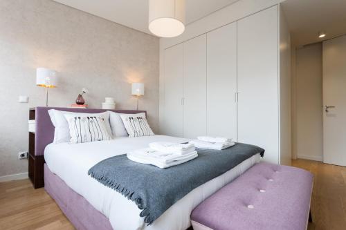 a bedroom with a large white bed with a purple seat at FLH Avenida da Liberdade Luxus in Lisbon