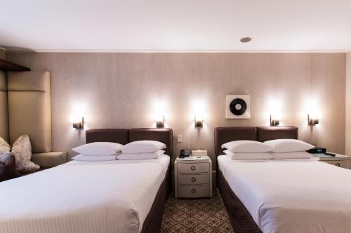 two beds in a hotel room with white sheets at City Club Hotel in New York