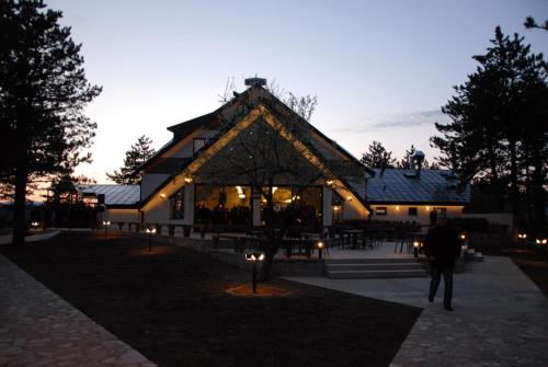 a man walking in front of a building with lights at Hotel Trebjesa in Nikšić