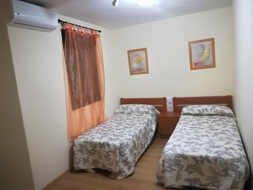 two beds in a small room with a window at APARTAMENTO PERGAR I - 4 PERSONAS DESDE 35e-WIFI in Granada