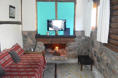a living room with a fireplace with a tv above it at Cabañas Rio Mendoza in Cacheuta