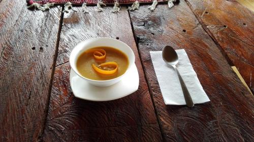 a cup of soup with a spoon on a wooden table at Finca Queveri in Orosí