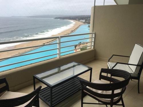 a balcony with two chairs and a table and a beach at Duplex Jacuzzi San Alfonso del Mar in Algarrobo