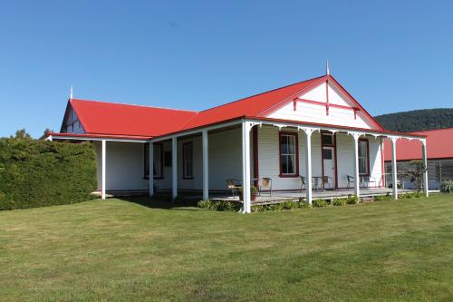 a white house with a red roof and a yard at Murrells Grand View House in Manapouri