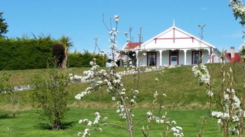 a house on top of a hill with white flowers at Murrells Grand View House in Manapouri