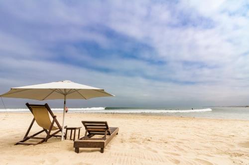 two chairs and an umbrella on a beach at Las Olas in Máncora