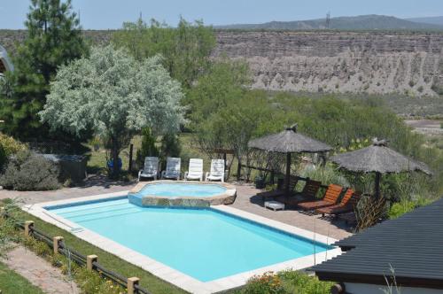 una piscina con 2 sillas y sombrillas en Cabañas Rio Mendoza en Cacheuta