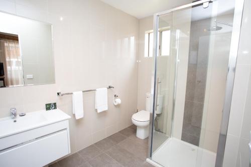 a bathroom with a toilet and a glass shower at Blue Whale Motor Inn & Apartments in Warrnambool