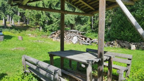 a picnic table and two benches under a gazebo at Malebná chalupa u Javorníku na Šumavě in Vacov