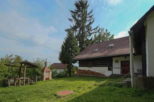 a house with a grass yard next to a tree at Malebná chalupa u Javorníku na Šumavě in Vacov