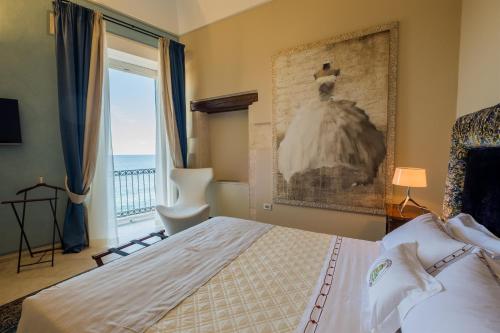a bedroom with a bed and a window with a dress on the wall at Hotel Ortigia Royal Suite in Siracusa