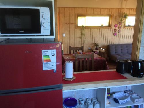 a kitchen with a red refrigerator with a microwave on top at Cabañas La Misión in Niebla