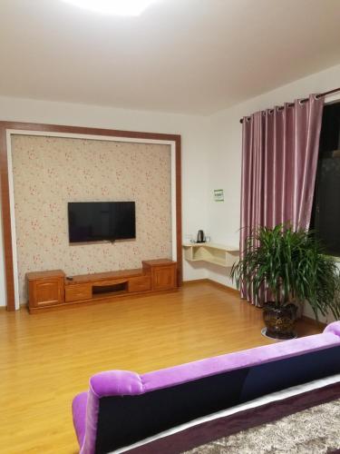a living room with a couch and a flat screen tv at Wuyuan Man Shan Inn in Wuyuan
